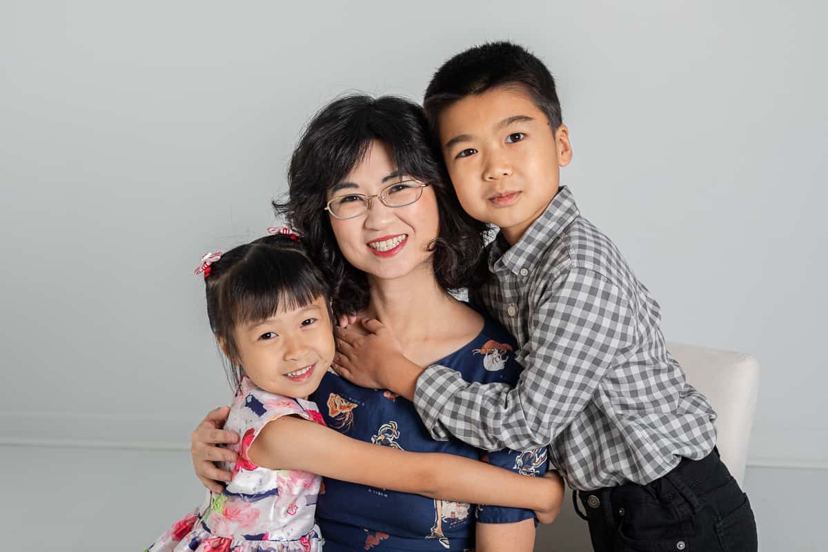 Two children hug mom in studio portrait